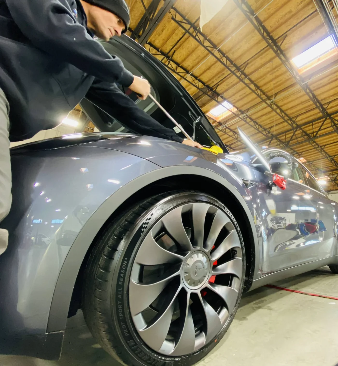 Technician working at the wheel arch of a silver Tesla